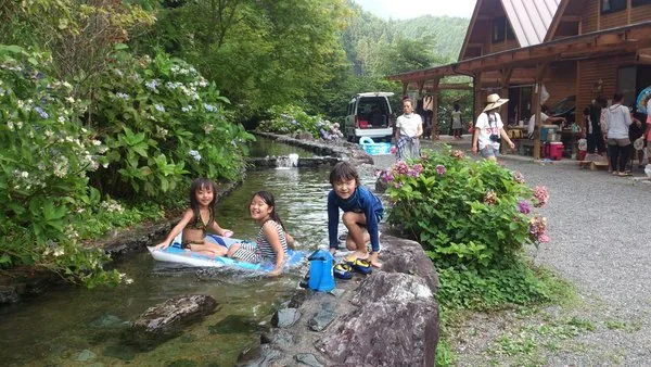 人工の小川で水遊びする子どもたち