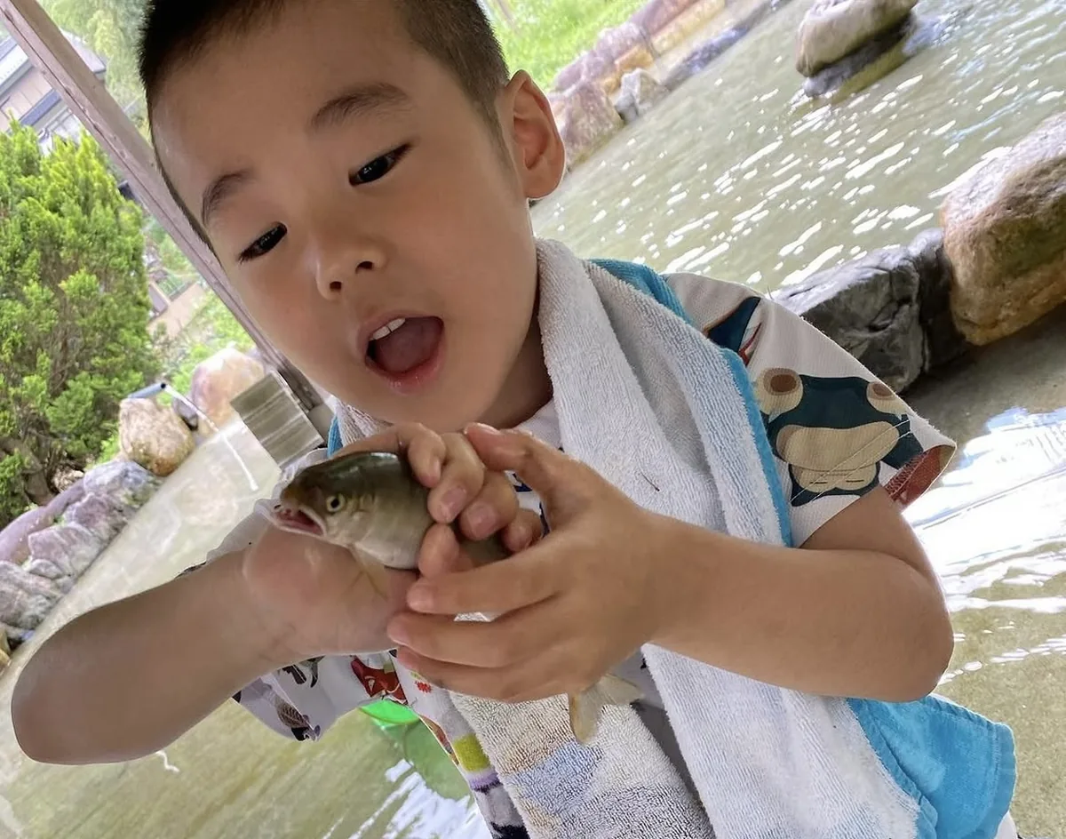 つかみ取り池でつかまえた鮎を、両手でつかんでいる子ども